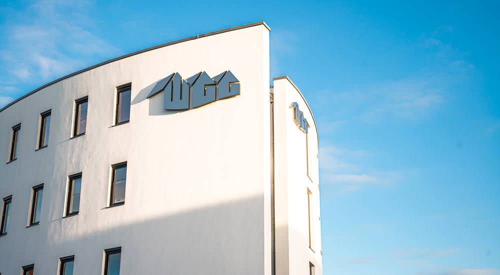 Gebäude der Wohnungsbau-Genossenschaft Greifswald eG mit WGG-Schriftzug vor blauem Himmel